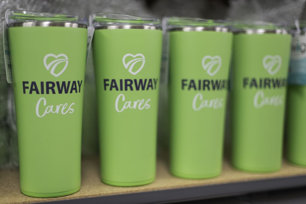 Bright green Fairway Cares insulated tumblers lined up on a shelf